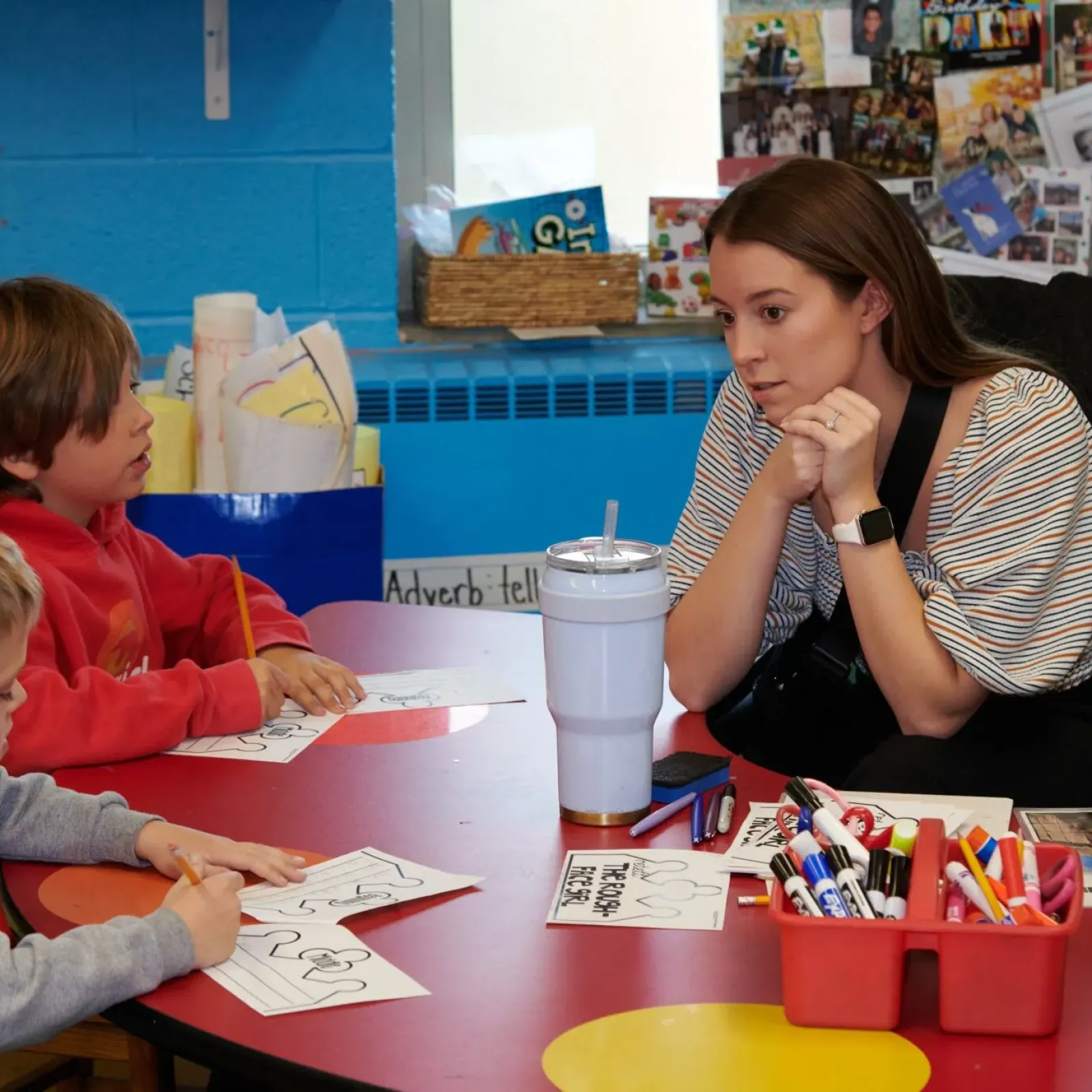 Teacher working with two students at a desk.