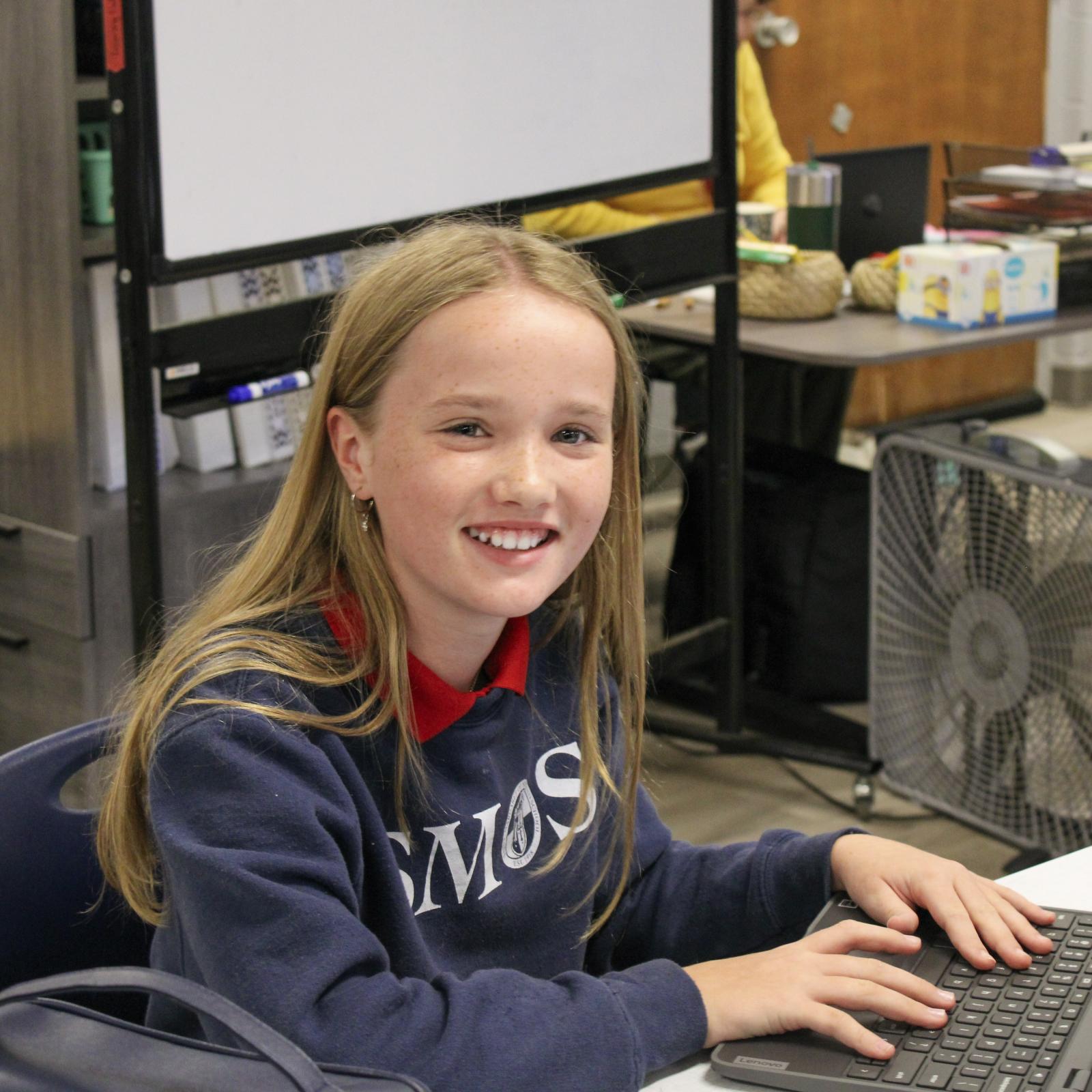 High schol student at desk working on a laptop
