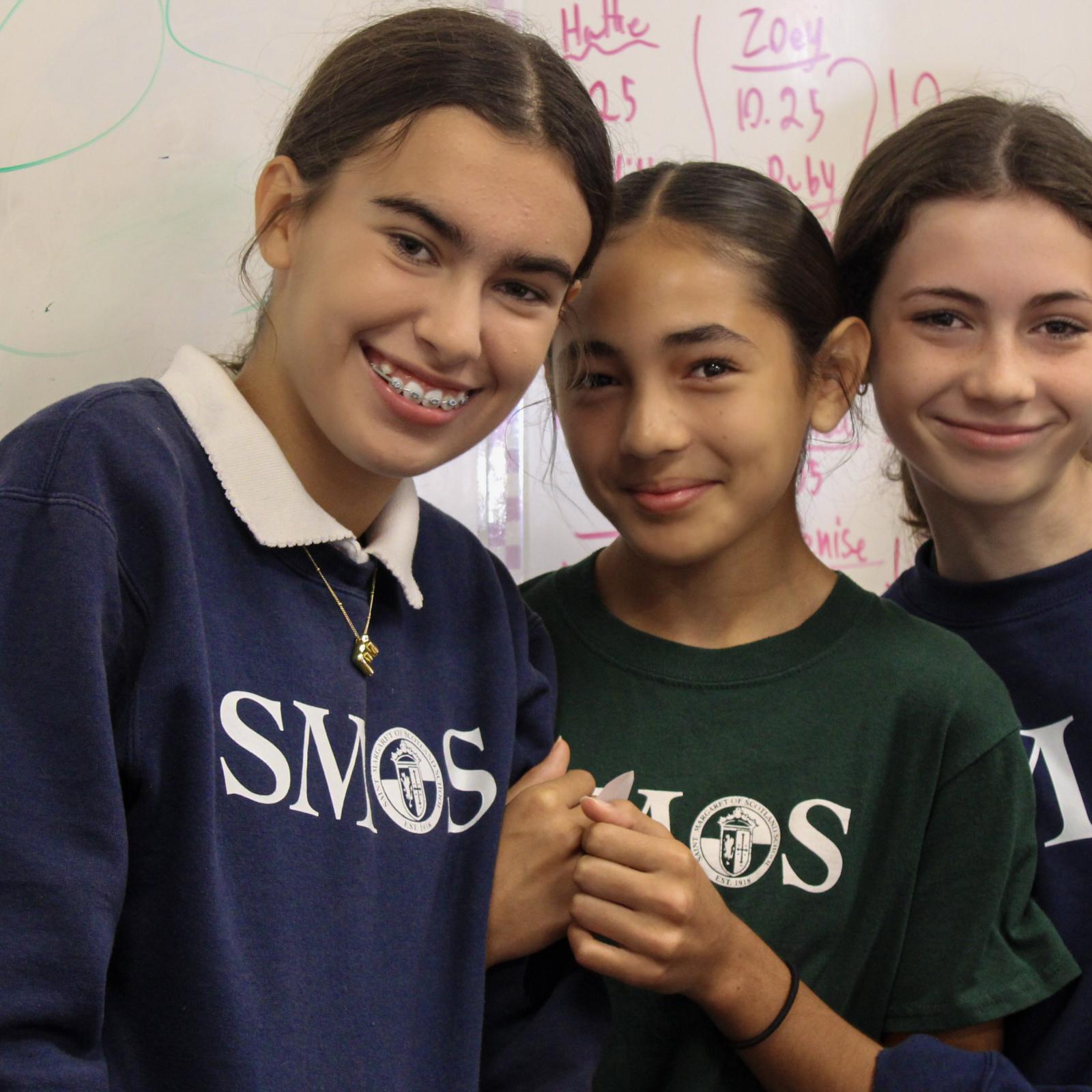 Three students in uniform smiling